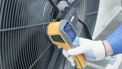 technician uses a thermal imaging infrared thermometer to check the condensing unit heat exchanger