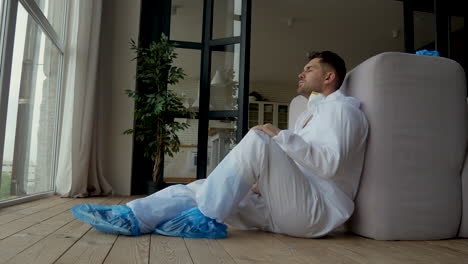 coronavirus pandemic. man resting after disinfecting a house. adult male tired sitting on the floor. covid-19.