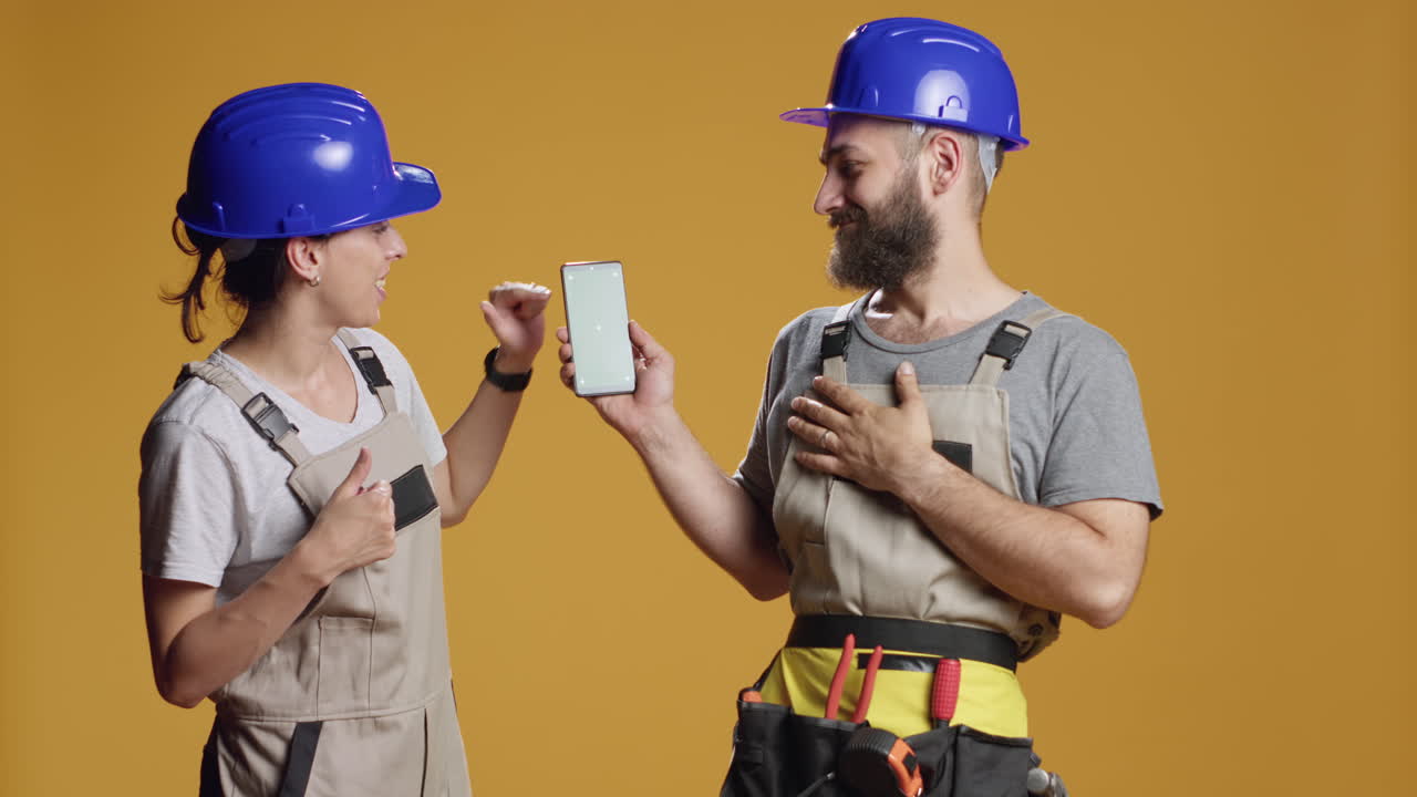 Portrait of building contractors pointing at smartphone