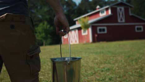 agricultor cargando un balde lleno de leche natural fresca, caminando en la granja rural rutina matutina estilo de vida fuera de la red