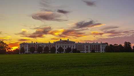 Tiro-Estático-Del-Parque-De-Hierba-Verde-Del-Castillo-De-Jelgava-En-Letonia-Con-Sol-Saliendo-En-Timelapse-En-El-Fondo