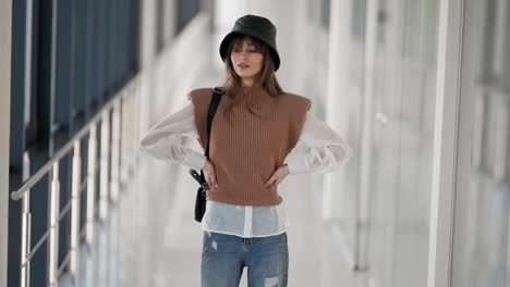 Fashionable-beautiful-girl-in-a-knitted-jacket-with-a-panama-on-her-head-and-a-leather-handbag-in-her-hands-poses-fashionable