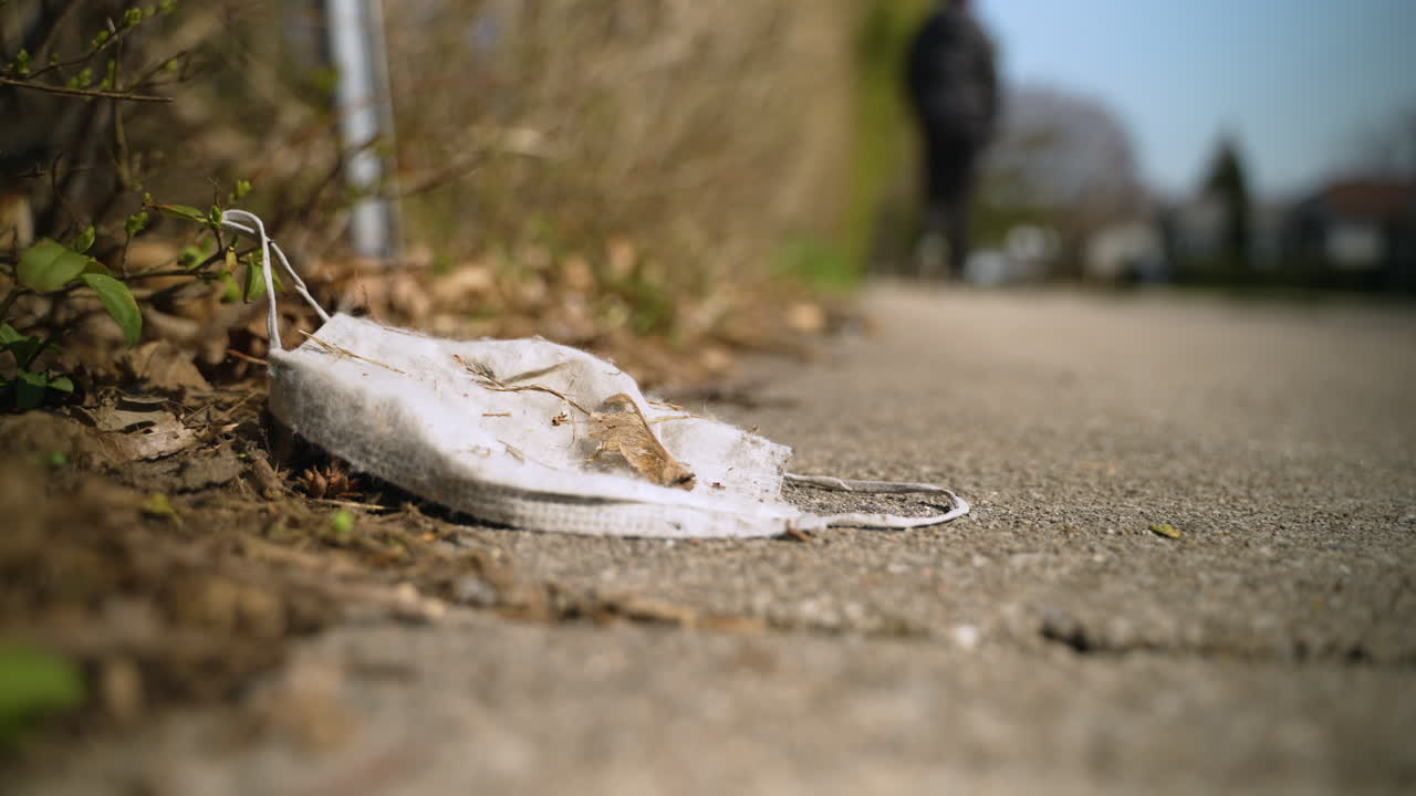 사람이 지나갈 때 보도에 버려진 더러운 안면 마스크