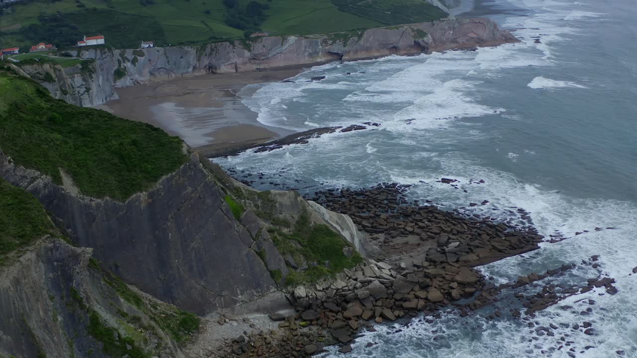 Aerial pan reveals sheer cliffs of Itzurun beach, rocky ocean coastline