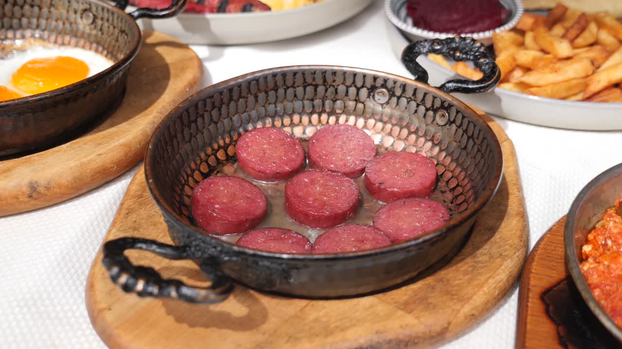 A close-up of a breakfast spread with sucuk and fried eggs