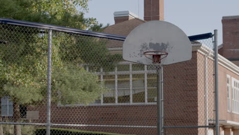 Viejo-Aro-De-Baloncesto-Y-Tablero-Trasero-En-Una-Cancha-Al-Aire-Libre-De-La-Escuela-Primaria-Con-Una-Sartén-Lenta-A-La-Derecha