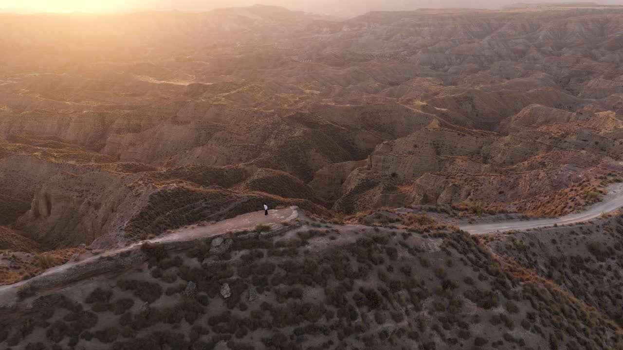 Man Standing on Cliff Overlooking Mountain Range at Sunrise
