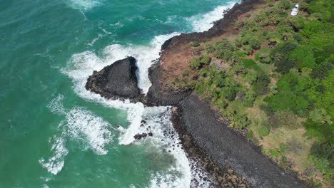 waves crashing on rocky shore of cook island in new south wales, australia - aerial shot