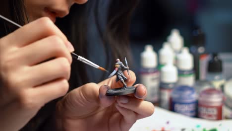intricate painting process: a close-up of a hand skillfully detailing a miniature figure with precision brushes and an array of vibrant paints