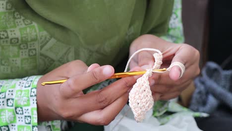 close up shot of a woman knits wool with her hands and sewing needles on a studio set, traditional manual needles knitting craft.