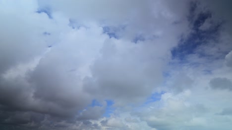 Fluffy-clouds-moving-away-from-camera-and-patches-of-blue-sky,-long-exposure-60x-time-lapse