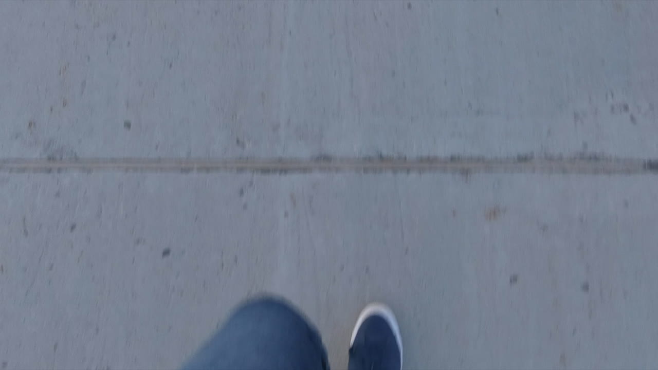 Editorial, high angle view of up part body, legs and feet of a person (guy) walking on sidewalk, outside in street. blue shoes and pants.