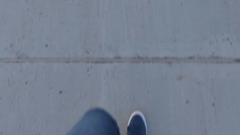 editorial, high angle view of up part body, legs and feet of a person (guy) walking on sidewalk, outside in street. blue shoes and pants.
