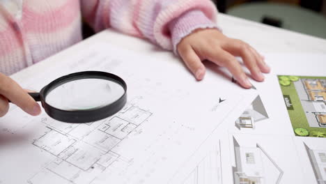 architect at the construction site checks house plan documents with a pencil to check structural design, correctness, and construction strength