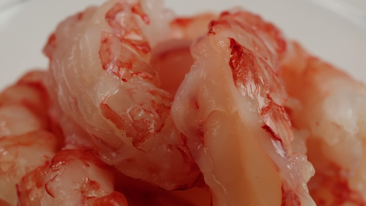 Gamberi per sashimi e gamberi sgusciati, disposti su un tagliere di legno, sono pronti per la cottura.