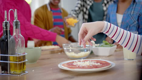 un grupo feliz y diverso de amigos adolescentes cocinando y haciendo pizza en la cocina, en cámara lenta