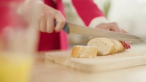 mujer con la ropa roja cortando una rebanada de pan blanco