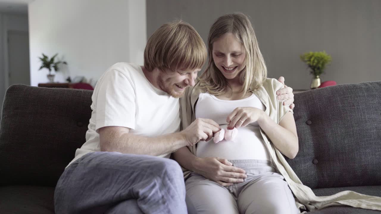 Happy young couple sitting on sofa and playing with booties