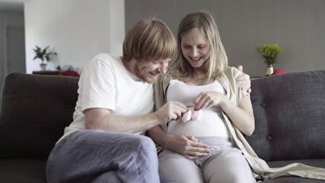 Happy-young-couple-sitting-on-sofa-and-playing-with-booties