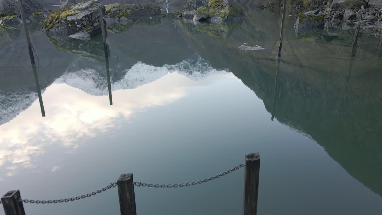 물 반사가 있는 장엄한 산악 호수의 작은 목조 부두, 돌리 앞으로 기울이기 샷