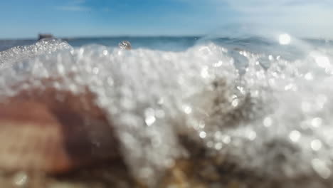 Zeitlupenaufnahmen-Vom-Meereswasser,-Das-Auf-Muscheln-Und-Kieselsteine-Spritzt