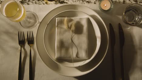 overhead of table setting with plate napkin cutlery and glass of champagne