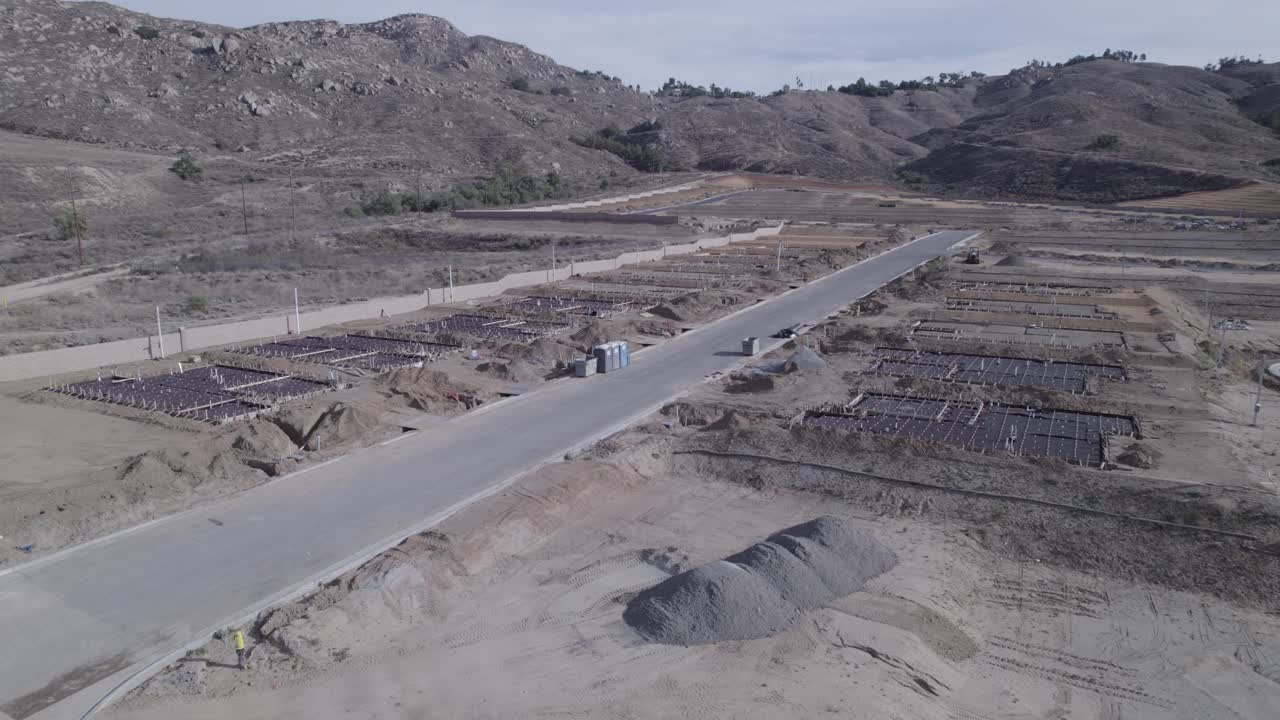 un vuelo lento de un avión no tripulado sobre un sitio de construcción de casas revela los cimientos puestos para las nuevas casas