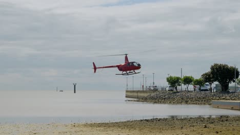 red helicopter landing in cairns esplanade lagoon on a cloudy day at slow motion in queensland australia