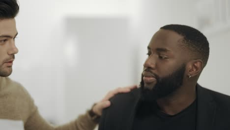 two serious men discussing working data in open space. white man patting shoulder