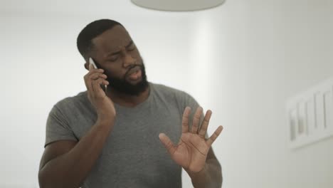 serious black man talking phone at home kitchen. young guy talking smartphone