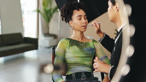 makeup artist applying makeup to model in studio
