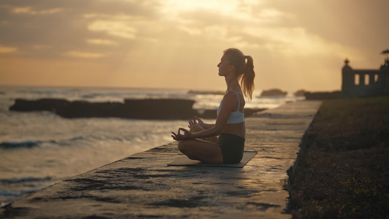 mujer en pose de loto de yoga meditando en la costa tropical durante el atardecer, el atardecer