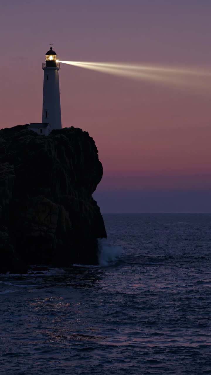 Un sereno video del tramonto di un faro su una scogliera rocciosa, ripreso da un'angolazione bassa.