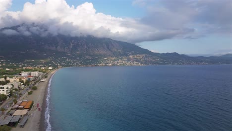 aerial high angle, wide view of seaside of kalamata, messinia, peloponnesus, greece. slow left pan drone movement, taygetos mountain covered with clouds on background 4k