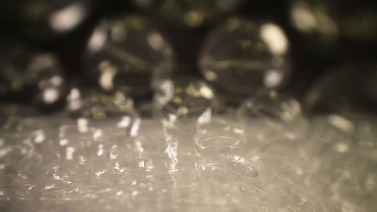 empujando rápidamente en una bolsa de plástico de burbujas, donde la bolsa está realmente cerca de la lente mientras cae en cascada, se aleja rodando a medida que avanza