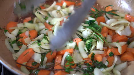 Close-up of a chef with flames cooking mixed colorful vegetables tossing them, restaurant kitchen
