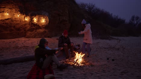 amigos disfrutando de una fogata en la playa por la noche