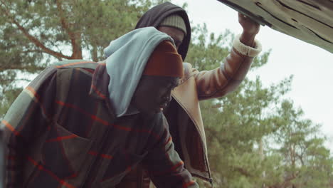 hombres afroamericanos mirando debajo del capó del coche y hablando