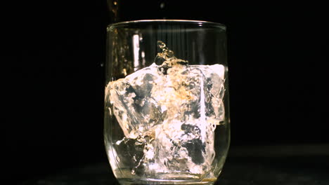 Whiskey-being-poured-into-a-glass-with-ice-cubes-