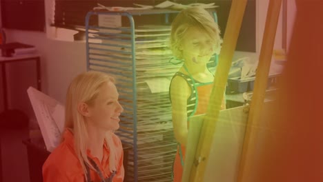 spots of light against caucasian female teacher teaching a girl how to paint at elementary school