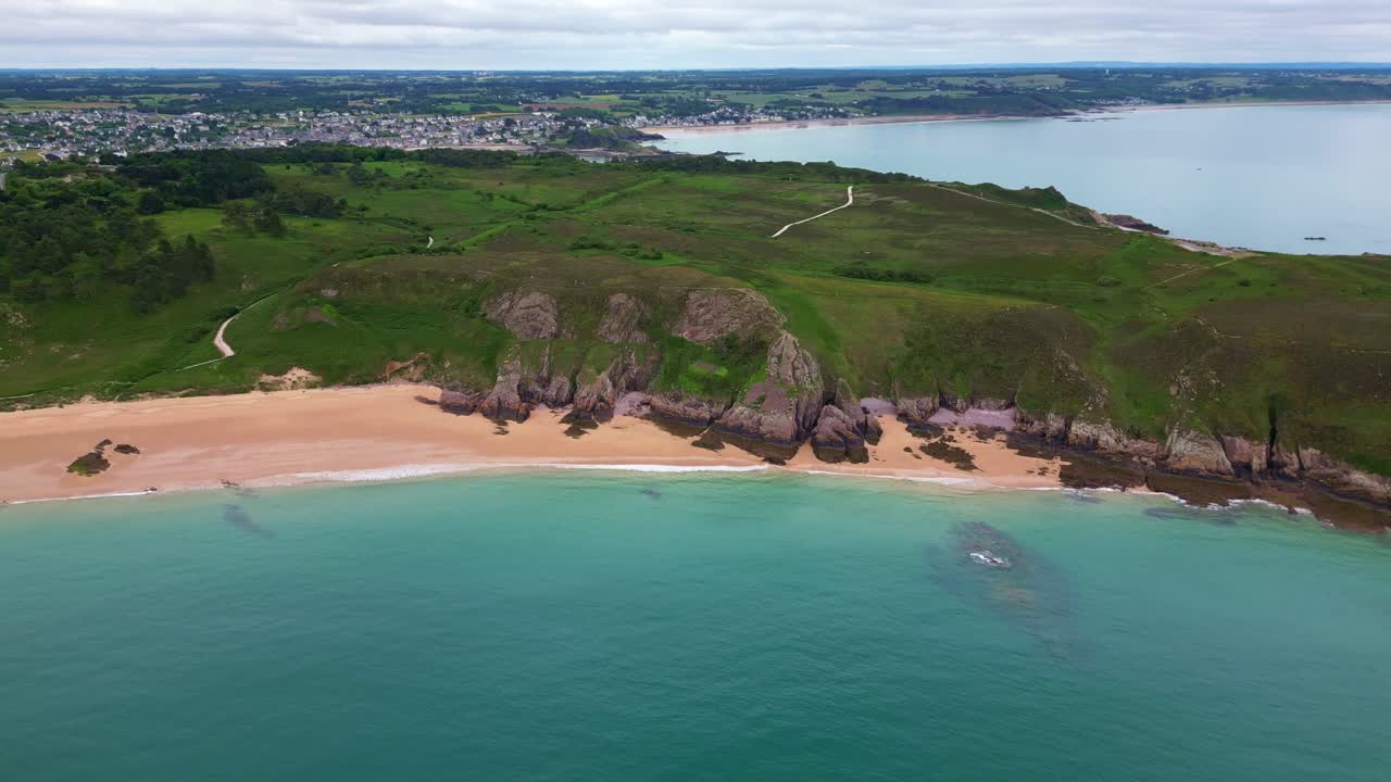 Aerial drone view of scenic coastline at Cap d'Erquy, revealing the town of Erquy in the background, Brittany, France