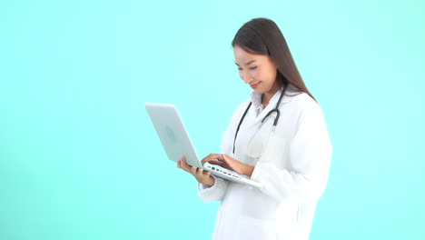 a young female healthcare professional holds a laptop in one hand and enters data with other, copy space