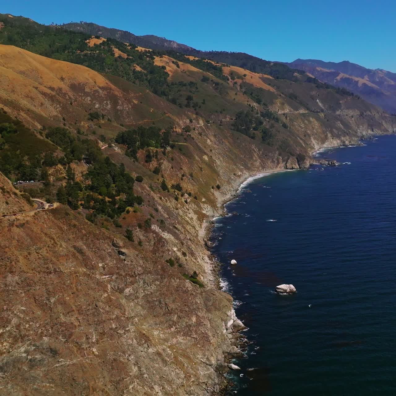 Flying over the mountains descending into the deep ocean. Wonderful scenery of amazing rocky landscape on sunny day in Big Sur Morro Bay, California, United States