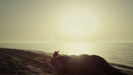 sporty girl training yoga on sandy beach. woman making plank pose at sunset