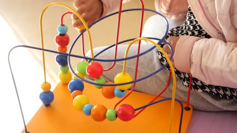 niño jugando con un juguete de laberinto de bolas coloridas