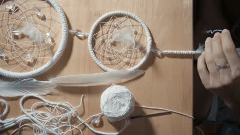 female hands creating dream catcher closeup, vertical angle