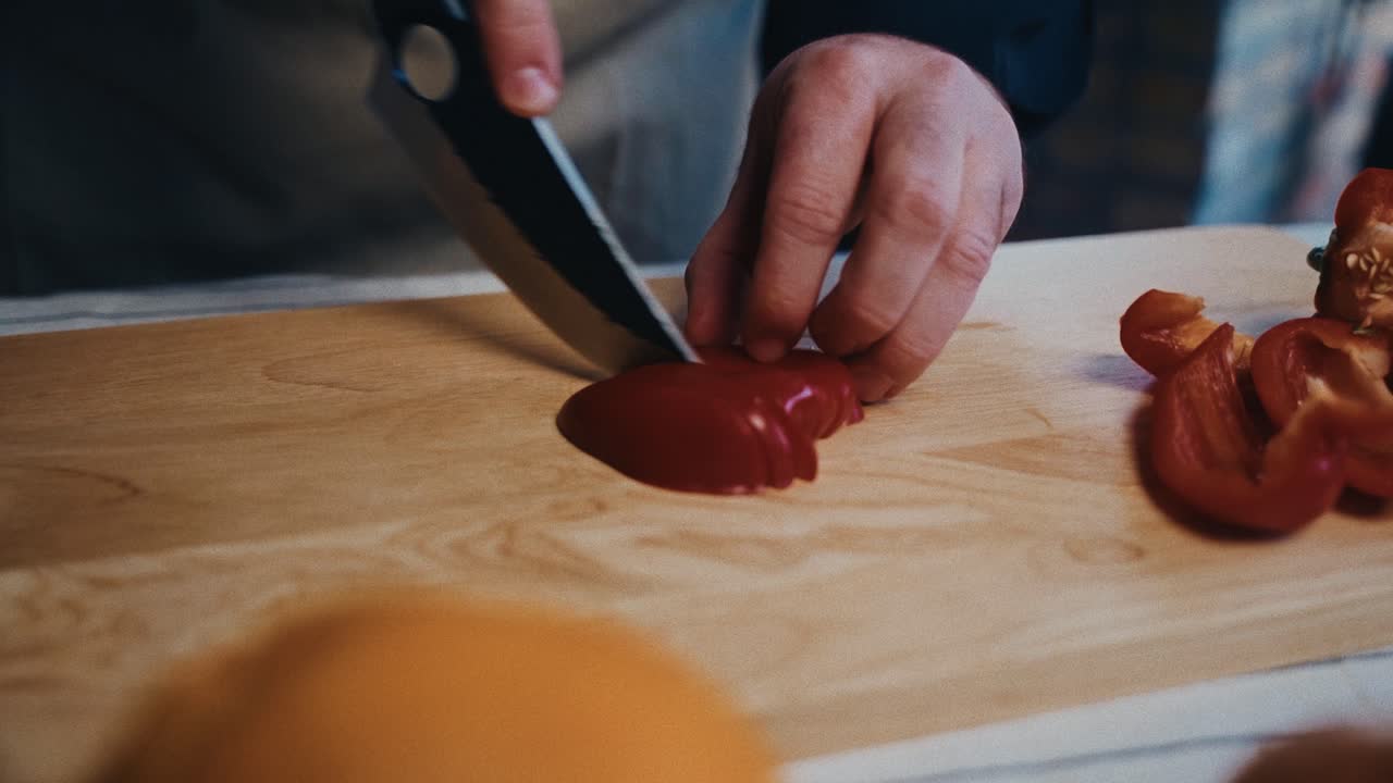 손에 초점을 맞추고 나무로 만든 절단판에 은 벨 페퍼를 잘라내는 사람