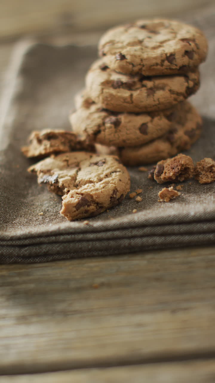 Vertical video of stack of chocolate chip cookies on cloth and wooden background