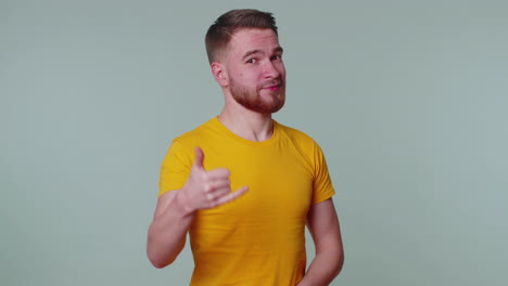 cheerful one man in t-shirt looking at camera doing phone gesture like says hey you call me back