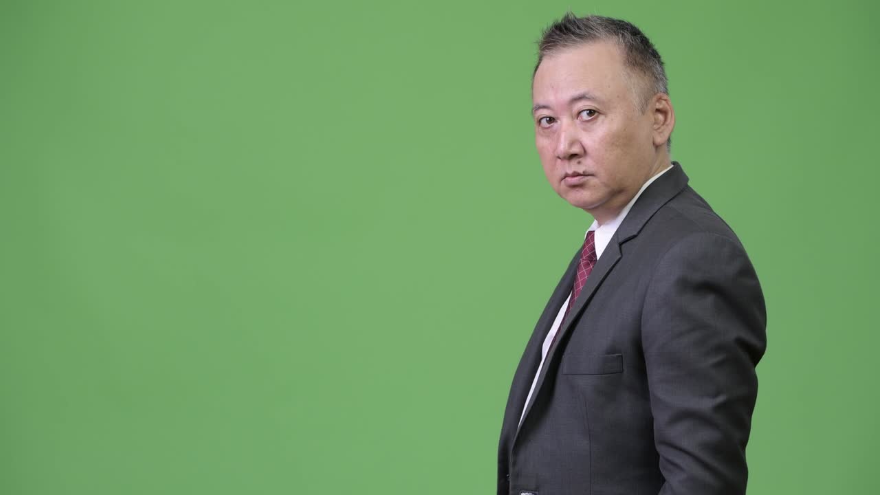 성숙한 일본인 사업가가 무언가를 보여주고 있습니다.